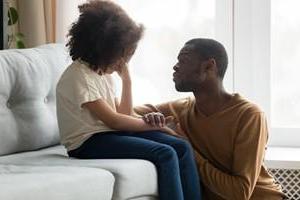 Man comforting small child on couch